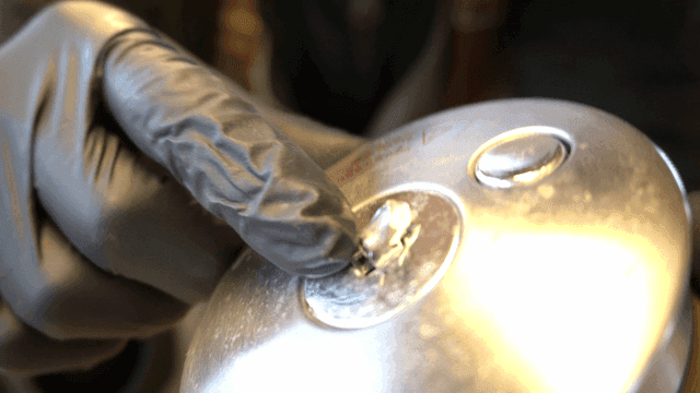 금속 부품을 검사하는 장갑 낀 손