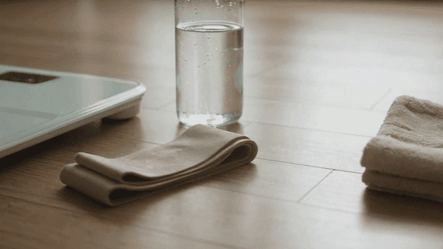A scale, water bottle, and towel on the floor