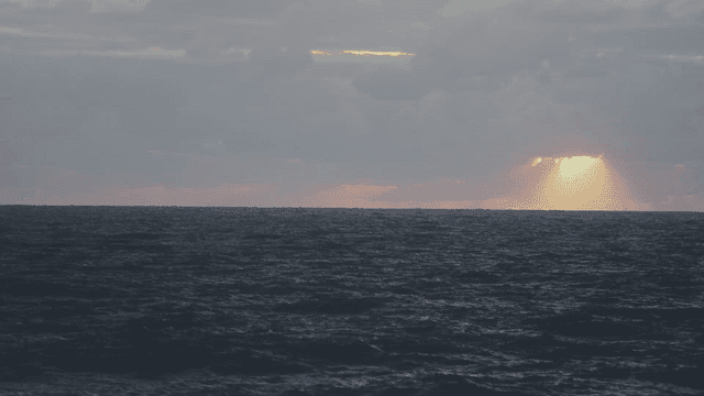 Sunlight falling through clouds over a wavering sea