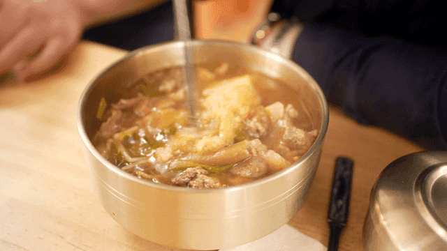 Mixing minced garlic into Korean beef soup using chopsticks