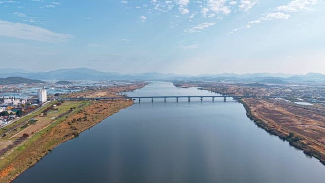 Wide river with a bridge and distant mountains