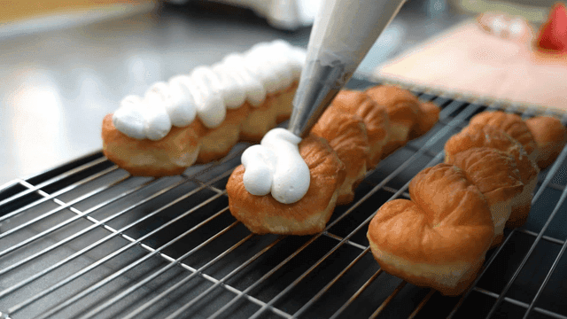 Cream being piped onto pastries