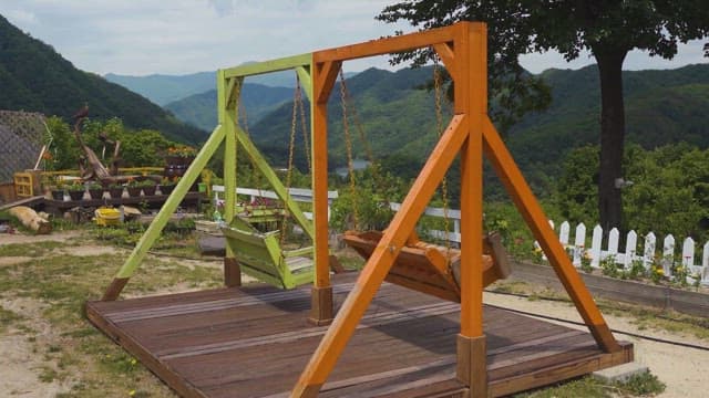 녹음이 우거진 산을 바라보는 정원의 그네