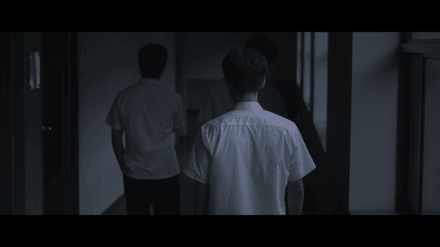 Male student turning back while walking in dark hallway