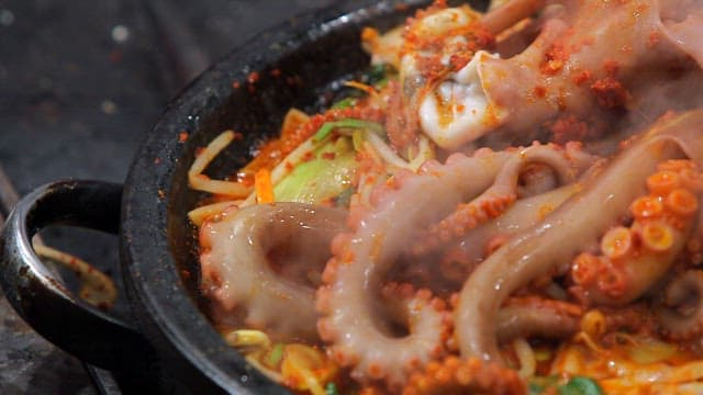 Spicy seasoned braised octopus cooking on a hot plate