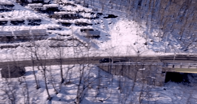 눈 덮인 산 옆 고가도로를 달리는 자동차