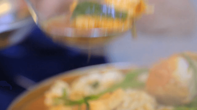 Scooping spicy codfish stew into a bowl with a ladle