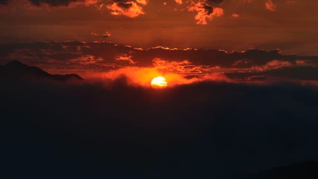 산과 구름 뒤로 해가 지는 모습