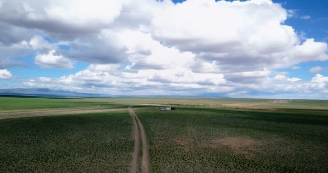 Vast green fields under a cloudy sky