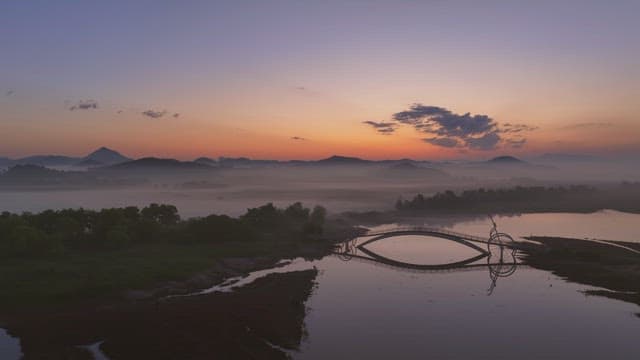 Serene river with misty mountain at sunset