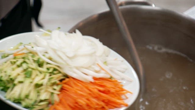 Broth made with chopped onions, carrots and cucumbers in a large pot