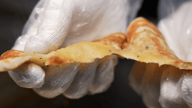 Gloved hands tearing hotteok