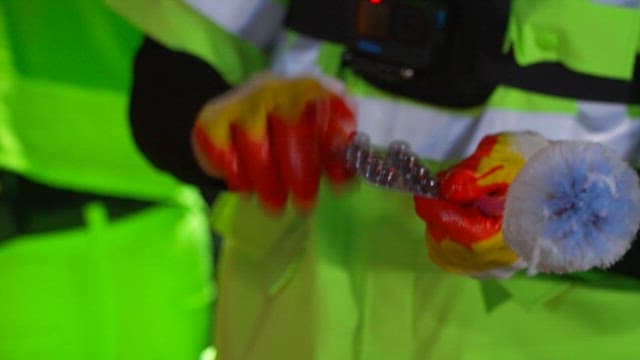 반사 조끼를 입고 밤에 폐기물을 검사하는 환경 미화원