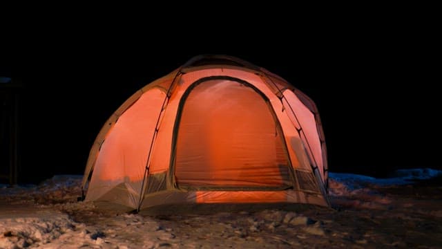A tent illuminated in the dark snowy night