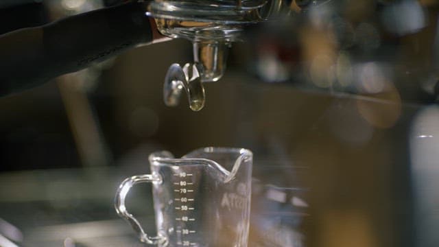 Espresso dripping into a glass measuring cup