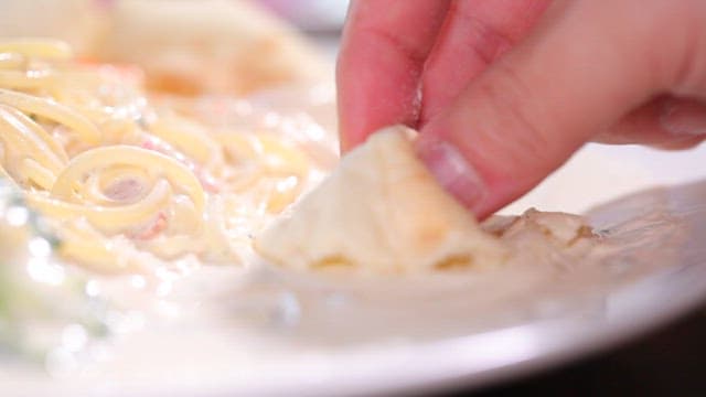 Dipping bread into creamy pasta sauce