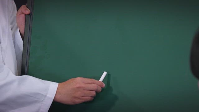 교실에서 분필을 사용하여 칠판에 글씨를 쓰는 사람