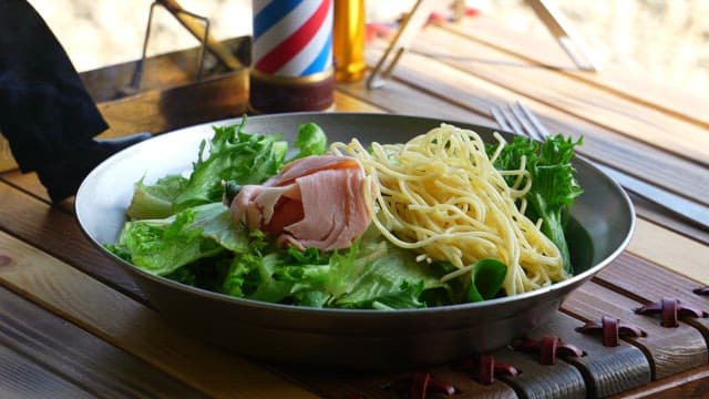 Fresh pasta with salad and ham on a wooden table