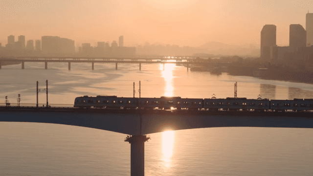 일몰 시간대에 강 위의 다리를 건너는 기차