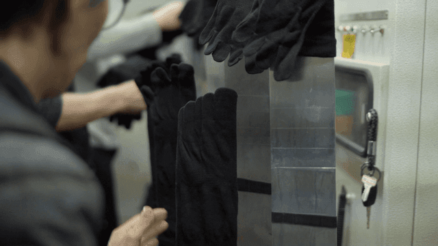Workers handling black socks in factory