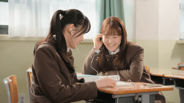 Students sharing earphones in a classroom