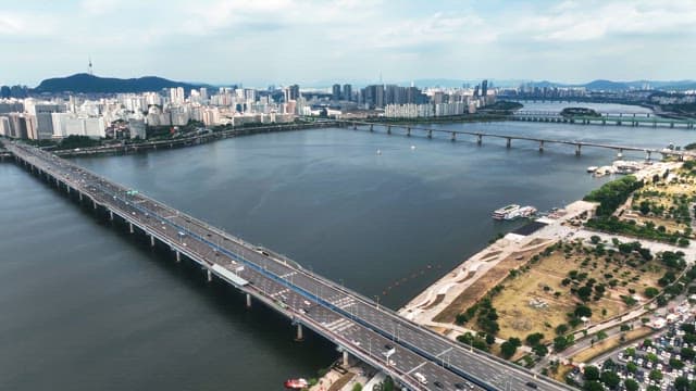 Serene river with a city skyline and long road