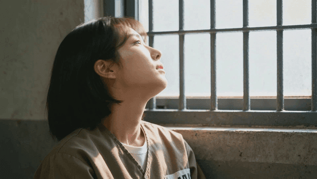 감방에서 철창 넘어 창문을 바라보는 여성 죄수