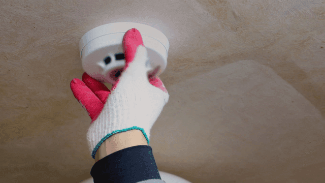 천장에 연기 감지기를 설치하는 사람