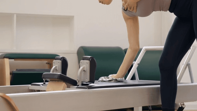 여성이 실내에서 운동 기구를 청소하는 모습