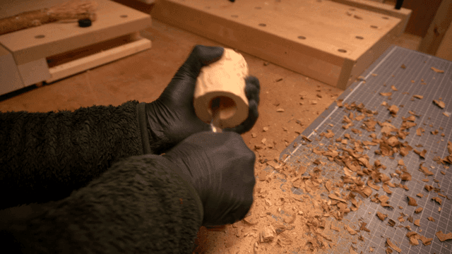 Craftsman carving wood with a knife in workshop