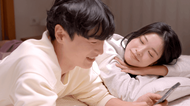 Couple spending time together on bed watching smartphone
