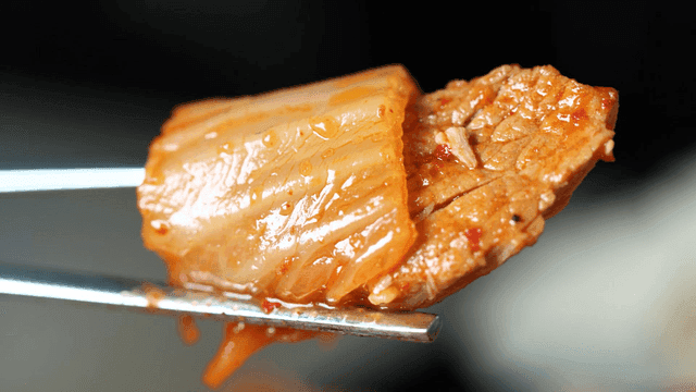 Kimchi and pork held with chopsticks