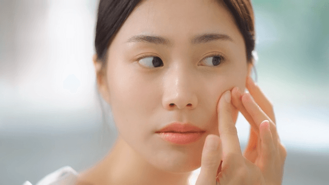 피부 트러블이 난 얼굴에 여드름 패치를 붙이는 여성