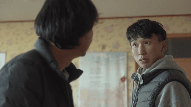 Two men talking with serious expressions indoors