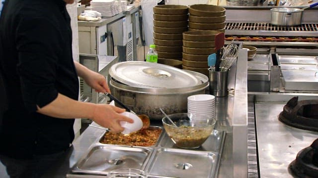 Chef preparing food in a bowl with soy sause with wild chive in the kitchen