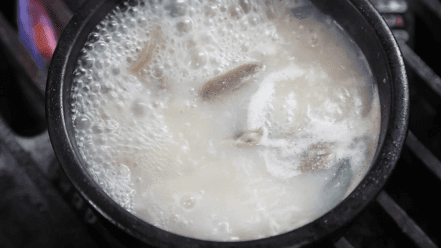 Beef soup boiling in earthenware pot over stove