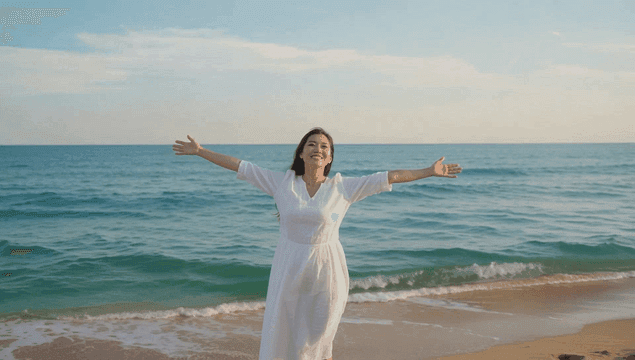 팔을 벌리고 해변을 즐기는 젊은 여성