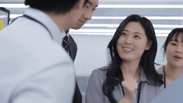 다같이 서서 웃으며 회의 문서를 체크하는 팀원들