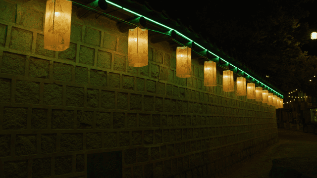Traditional lanterns illuminating a stone wall at night