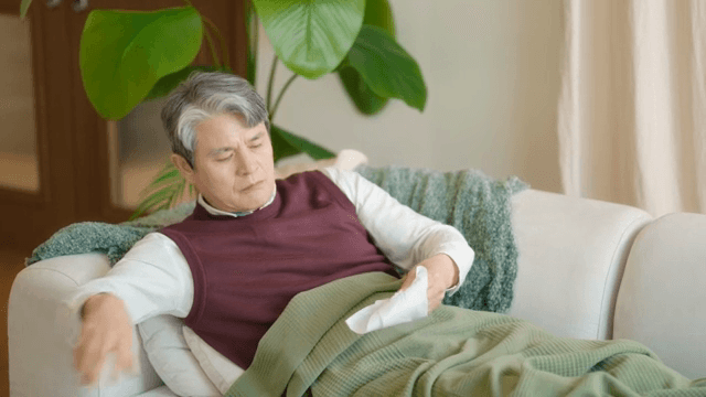 소파에 누워 기침을 하는 노인