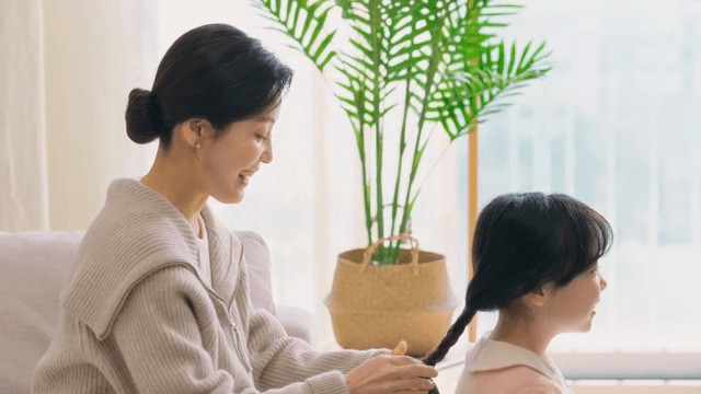 Mother braiding her daughter's hair