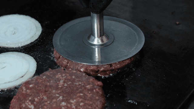 Burger patties and onions cooking on a grill