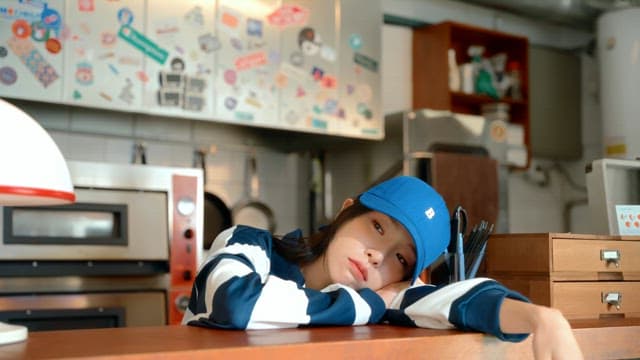 Woman in a blue hat bored at the counter