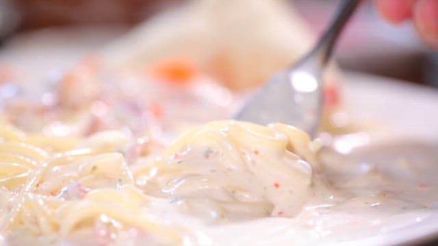 Creamy pasta being lifted with a fork