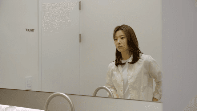 핸드폰을 보며 화장실을 나서는 여성