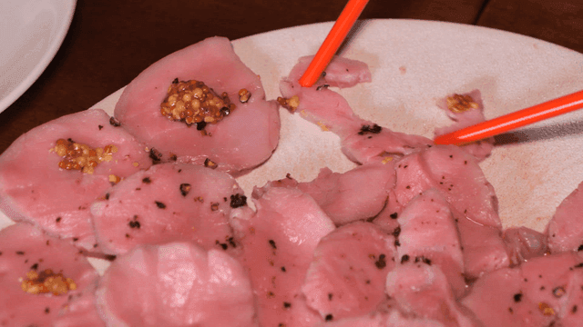 Woman uses chopsticks to tear thinly sliced ​​sirloin topped with mustard.