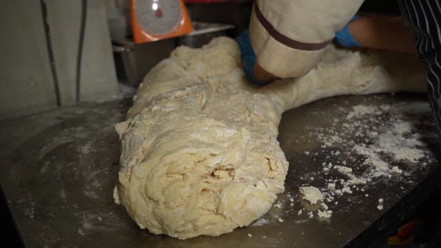 Dough being kneaded on a metal table