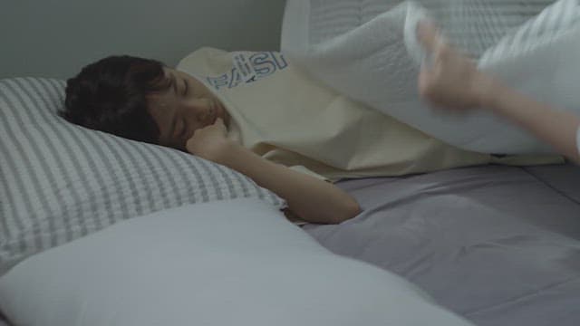 어두운 방에서 자고 있는 딸에게 이불을 덮어주는 어머니