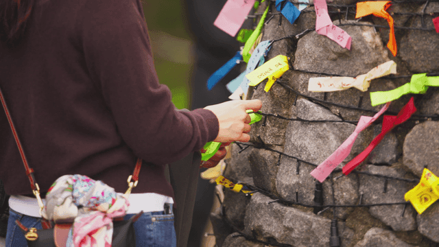 돌담에 색색의 리본을 묶는 사람