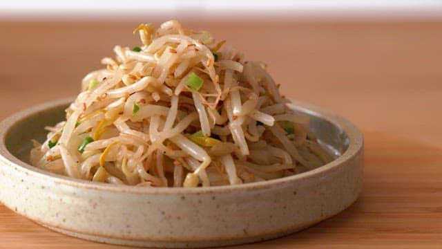 Bean sprout seasoning in a ceramic bowl on a wooden table